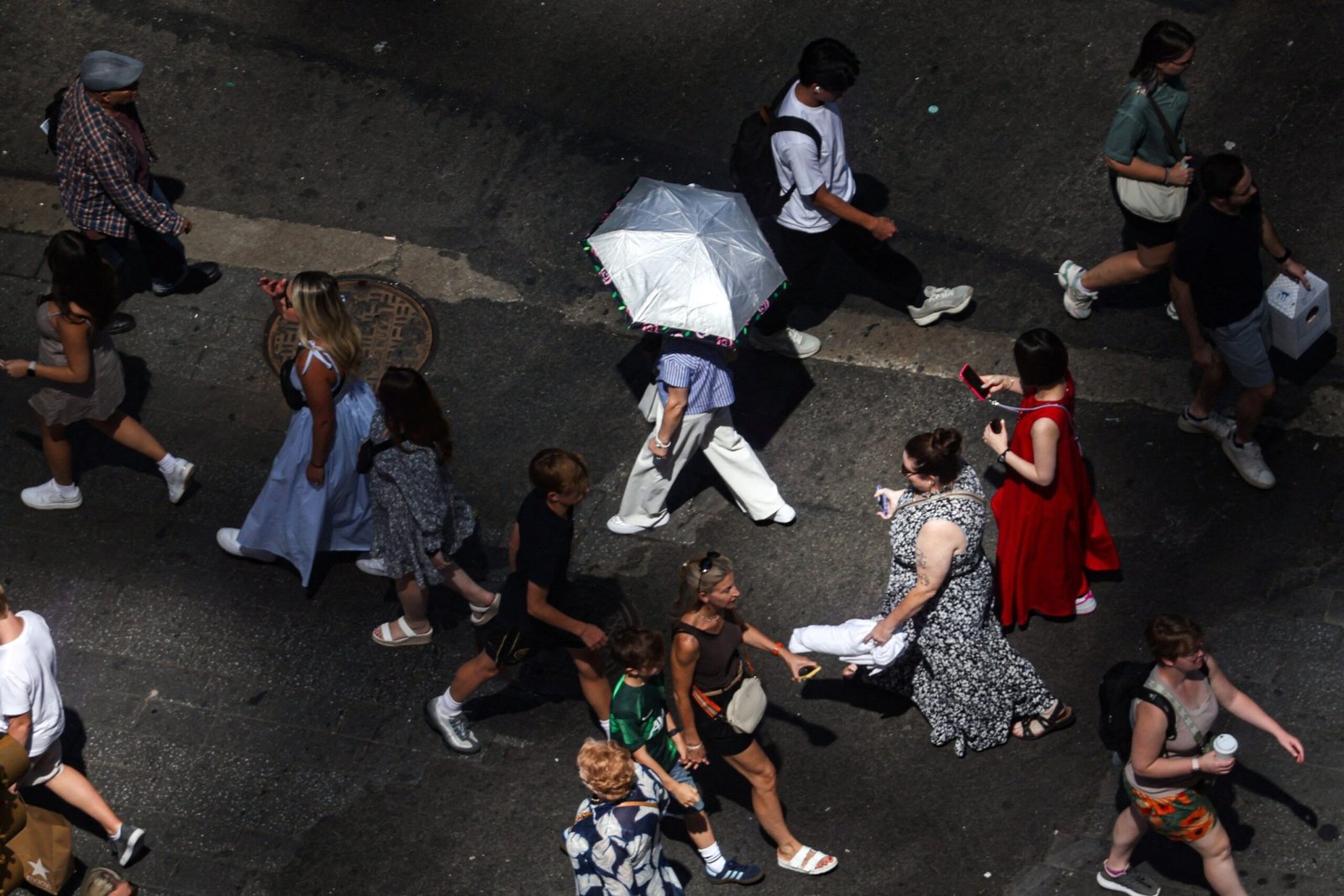 Photo: pedestrians, including a person holding an umbrella to block UV rays, walk on Times Square in New York